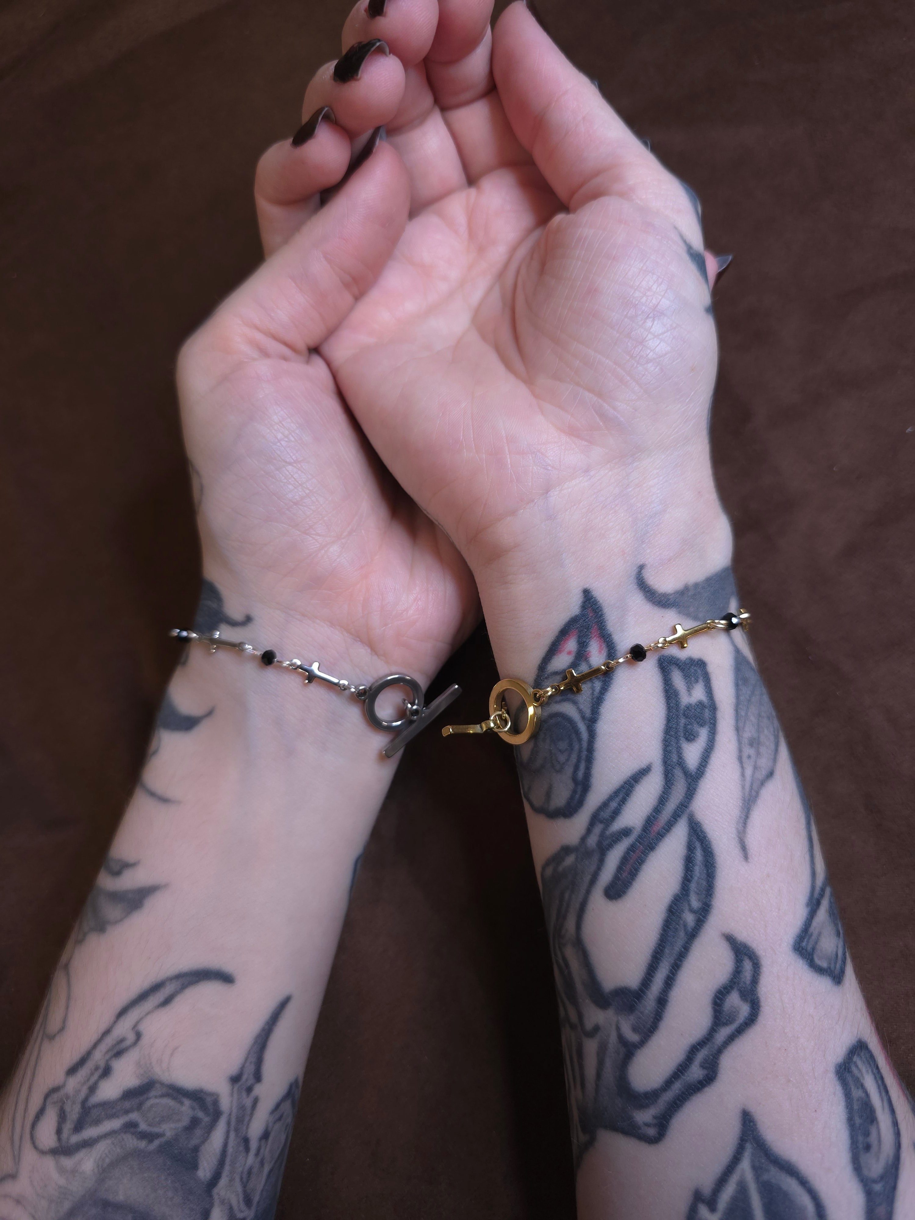 Two hands with tattoos holding each other against a brown background